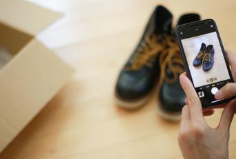 An adult capturing a photo of a pair of shoes using their phone