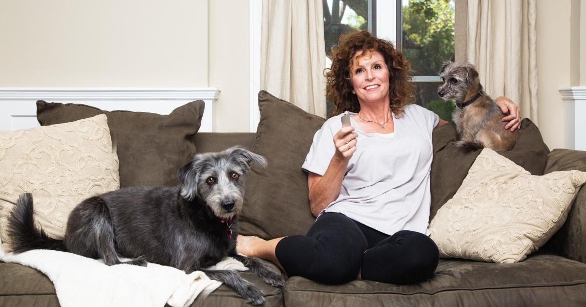 adult female watching tv with dogs on sofa