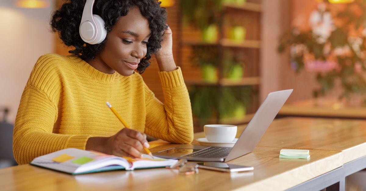 african american man with headphones doing homework while using laptop