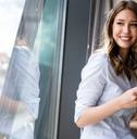 A business woman holding a notepad and smiling while standing in an office. 