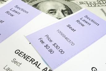 Two concert tickets shown on top of $100 bills.