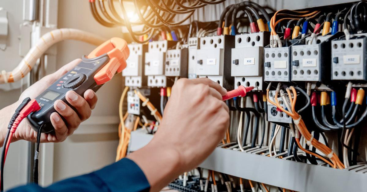 electrician using multimeter on electric cabinet