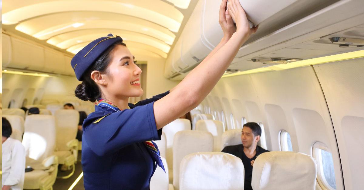 female flight attendant closing luggage compartment