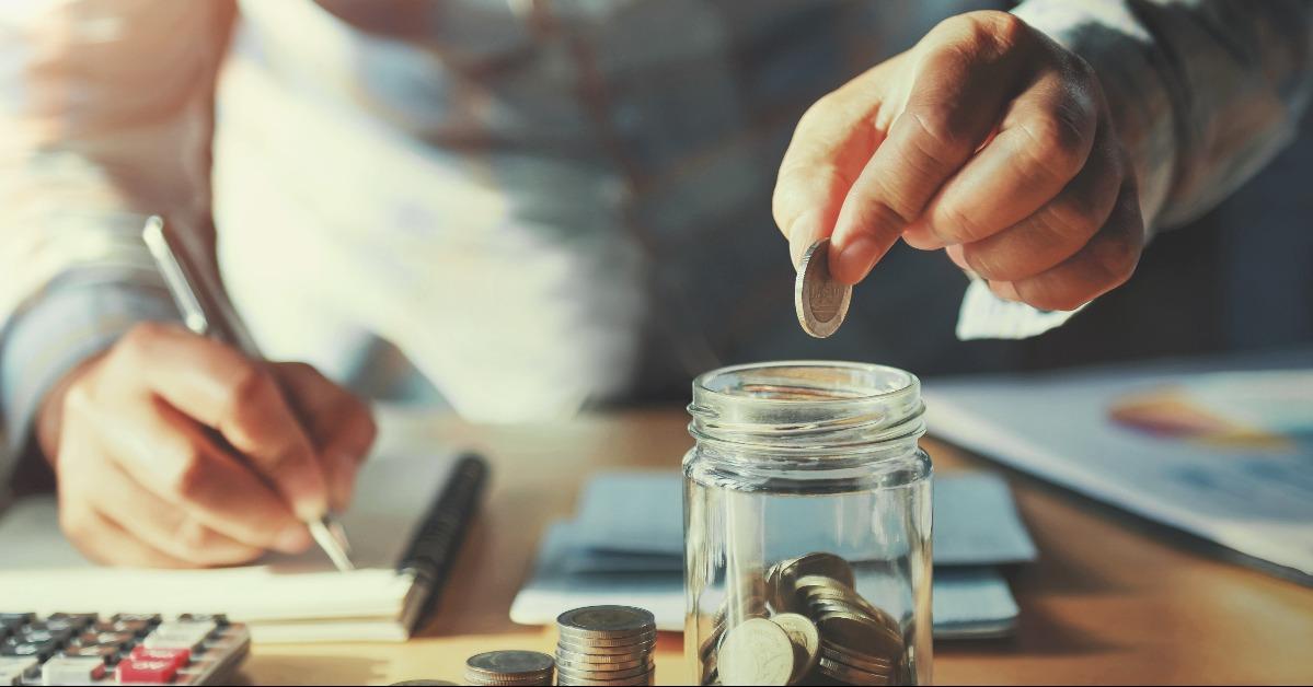 hand holding coins putting in jug glass