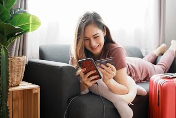 happy woman holding credit card and phone with luggage