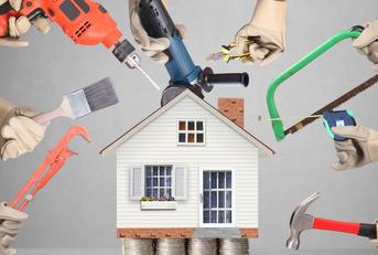 Hands holding up various tools, such as a drill and a paintbrush, around a model of a house that&#x27;s sitting on stacks of quarters.
