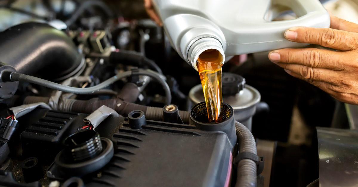mechanic pouring oil into engine