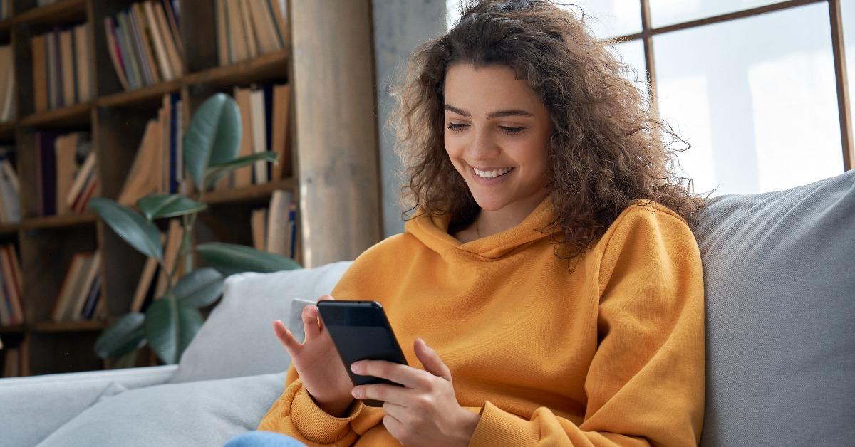 millennial hispanic teen girl holding smartphone at home