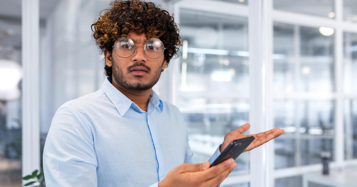 nervous man holding smartphone at work