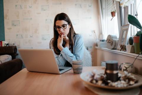 Pensive woman looking at laptop