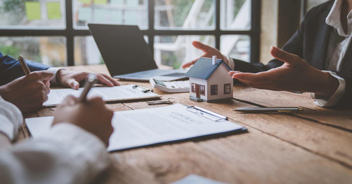 real estate agent talking to clients using hand gestures as they sign contract