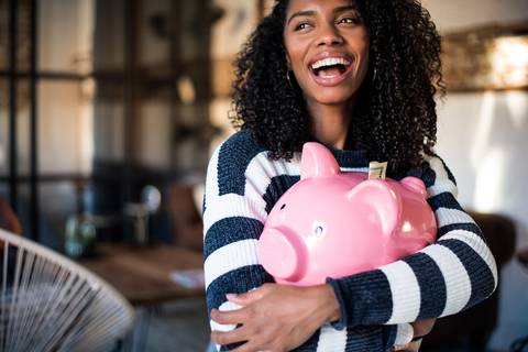 Smiling woman holding piggy bank