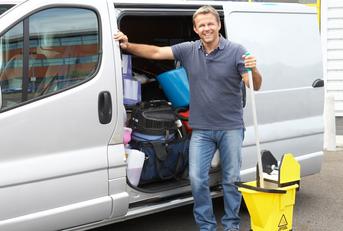 Man standing outside a van holding a mop