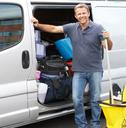 Man standing outside a van holding a mop