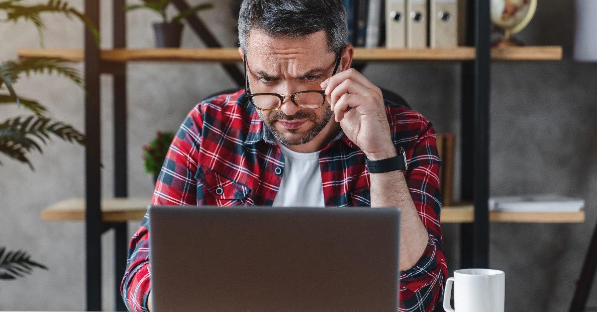 worried buisnessman squinting eyes at laptop