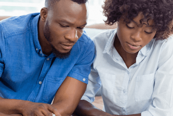 A couple sits at their table, going over their bills.