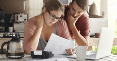 A concerned couple looks over their bills together. 