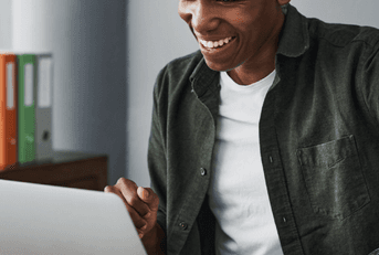 Man smiles while using his laptop. 