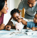 A family gathers at the table, counting money from a piggy bank.