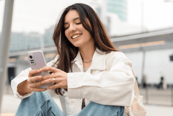 Smiling woman sitting and looking at phone