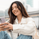 Smiling woman sitting and looking at phone